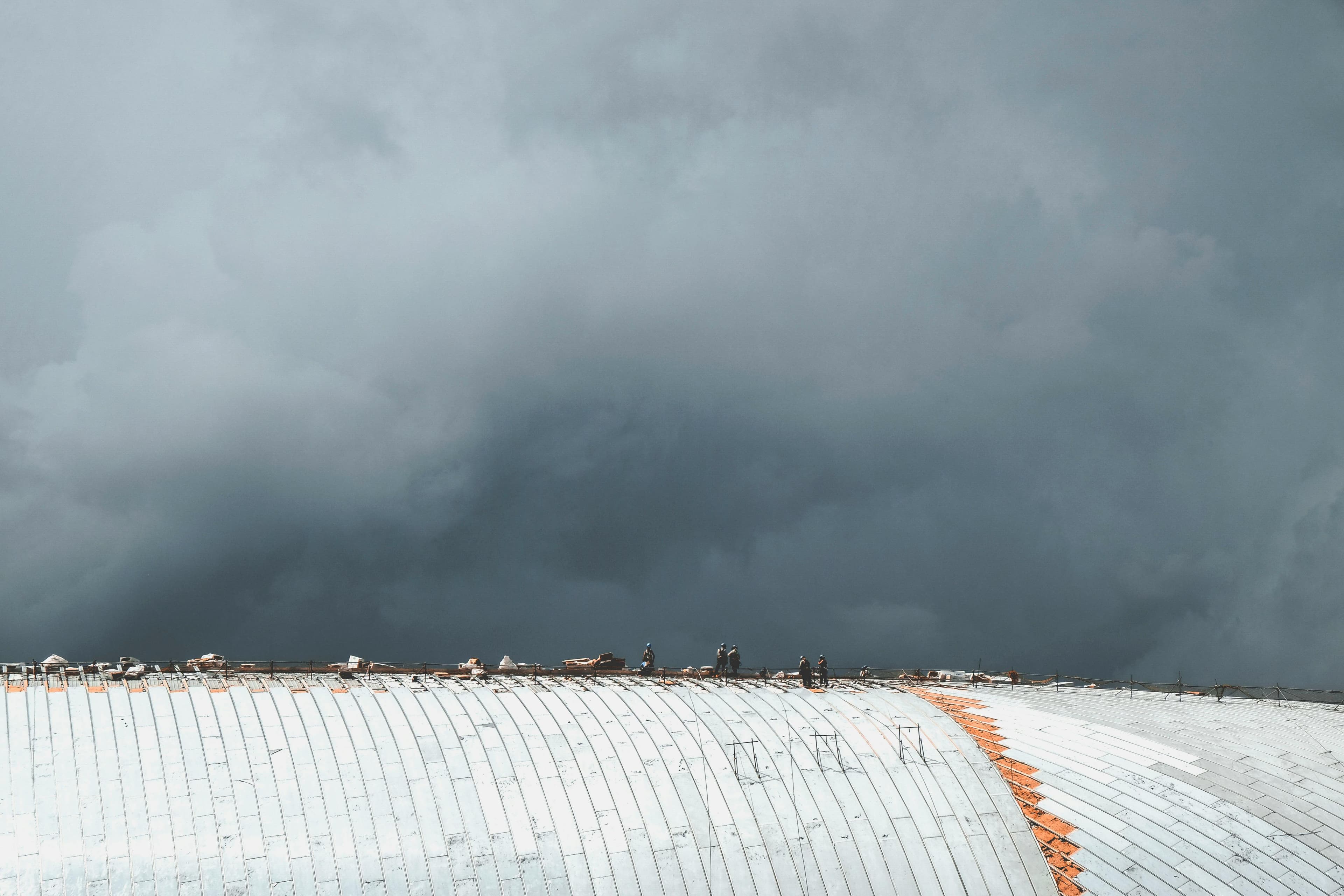 Workers on a rooftop under storm clouds